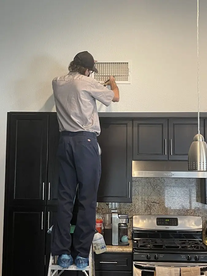 Technician inspecting an air vent during HVAC service in Kinnelon